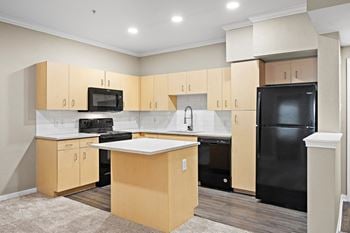 An empty kitchen with black appliances and wooden cabinets